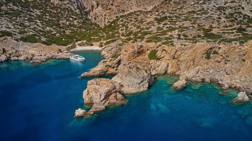Palatia Beach, Palatia, Clear blue water and rocks in a quiet bay with boats, boat tour Saria,
