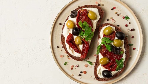 Breakfast, sandwiches with dried tomatoes, olives, and cheese cream, top view