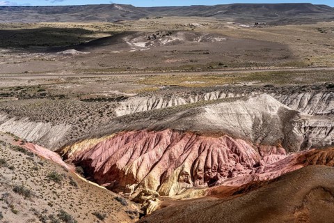 Eroded rock formations with reddish-yellow sediment layers, dry steppe landscape with table