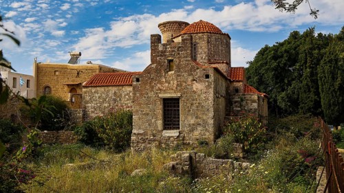 Old church with tiled roof, surrounded by green meadow and historic walls, Rhodes Old Town, Rhodes,