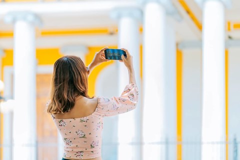 Girl taking photos of the Granada cathedral with cell phone. Young tourist taking photos of a