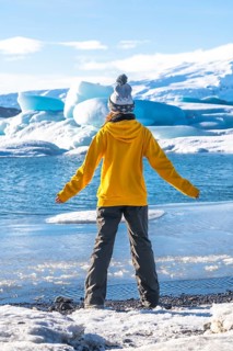 A woman with her back turned on the frozen lake Jokulsarlon during her vacation in Iceland,