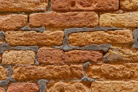 Close-up view of a rustic brick wall, showcasing its unique textured pattern with rough surfaces.