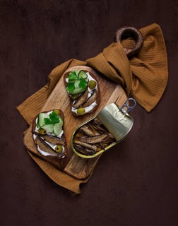 Sandwiches, black bread with sprats, cream cheese, cucumbers, on a cutting board, top view,