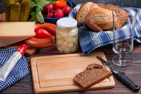 Rustic arrangement with sausage, cheese, gherkins and bread on a laid table