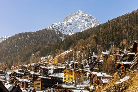 Snow-covered hotels and chalets built into the hillside, with the snow-capped summit of Sex de