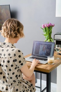 Back view of a woman making video call to business partner using laptop, looking at screen with