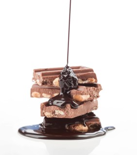 A tempting visual of rich chocolate syrup cascading over stacked almond filled chocolate bars. The