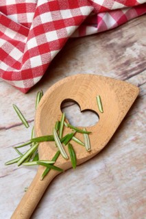 Rosemary, plucked rosemary leaves in wooden spoon