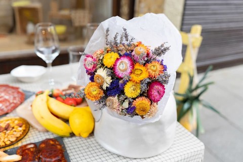A vibrant bouquet of dried flowers adds charm to a table adorned with fresh fruit and delicacies.