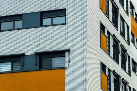 A modern building facade with a distinct design, a white brick wall with sleek, dark windows and a
