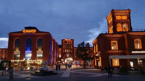 Lively evening square with illuminated brick buildings, Manufaktura, Lódz, Lodz, Poland