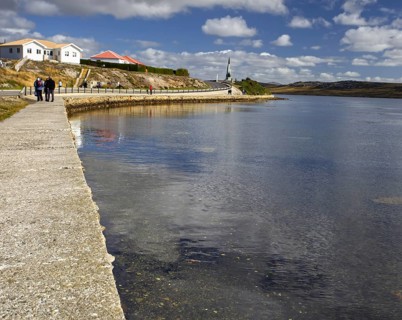 Long cobbled path along the sheltered bay, with houses in the distance under a wide sky with