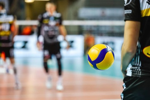 Volleyball ball flying near player before service with playing field in the background