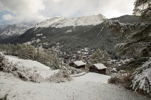 A picturesque view of Zermatt village in summer, surrounded by snow-covered mountains and lush