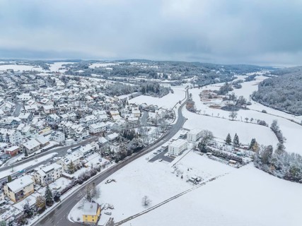 Aerial view of a snow-covered village with streets and houses under a grey sky, Aidlingen,