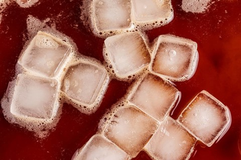 Top view of transparent ice cubes floating in rich, dark cold brew coffee. The iced beverage