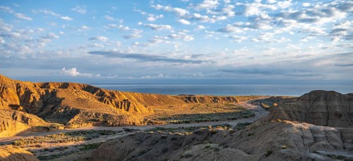 Landscape of eroded hills at sunrise, badlands, Issyk Kul Lake in the background, Canyon of the