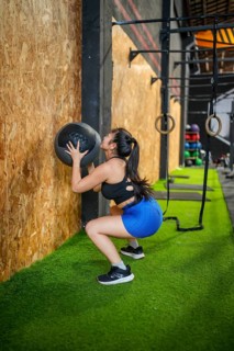 Full length side view of an asian sportive woman working out in a gym using medicine ball