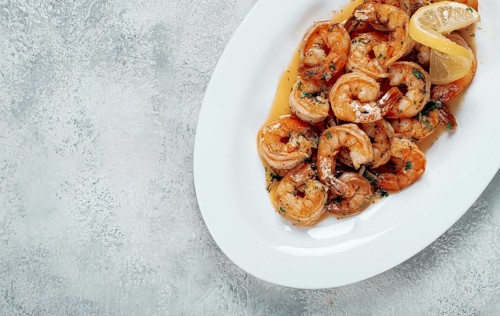 Fried tiger prawns, jumbo, in garlic sauce, in butter, with herbs, on a white plate, homemade, no