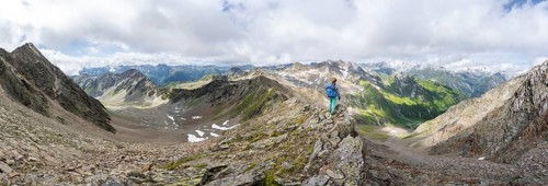 Panorama mountaineer on a steep rocky ridge, at the summit of Lasörling, view of mountains of the