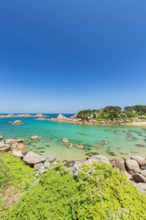 Beach with rocks and sand at the Plage Saint Guirec, with clear blue sky and colors as in the