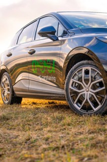 Close-up of a black car with highlighted tyres and logo at sunset, e-car sharing, Deer Mobility,