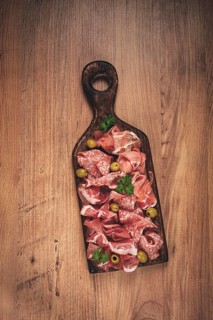 Assortment, sliced meat appetizer, prosciutto, salami and ham, with olives, on a wooden board,