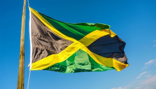 The flag of Jamaica flutters in the wind, isolated against a blue sky