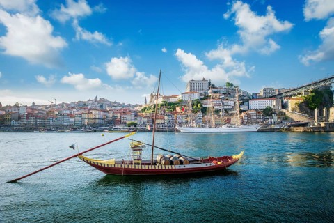 View of Porto city and Douro river with traditional boats with port wine barrels and sailing ship