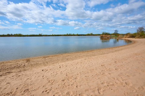 A quiet sandy beach on a lake under a blue sky with white clouds, Altmühlsee, Muhr am See,