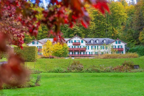 Large country house in green surroundings, surrounded by autumnal trees and shrubs, Grandhotel