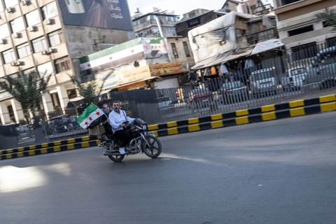 Damascus, Syria. December 5th 2025. A Syrian man and woman ride a motorcycle with a Syrian flag