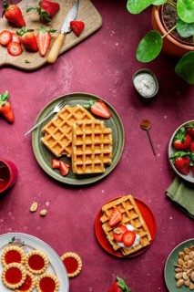A cozy rustic breakfast scene featuring homemade waffles and fresh strawberries. Served with nuts