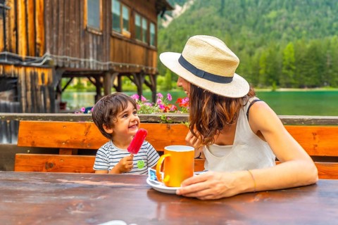 Happy mother and son savoring a lakeside snack in the stunning dolomites of italy during a warm