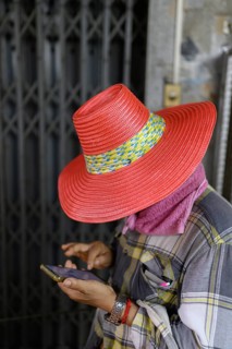 A local street vendor checks his phone in an alleyway near Yaowarat Road, Chinatown, Bangkok,