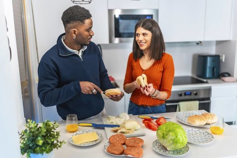 Young multiethnic couple preparing burgers in a modern kitchen, enjoying their time together