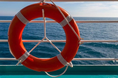 An orange-coloured lifebuoy hangs from a railing in front of a wide sea horizon, Norway