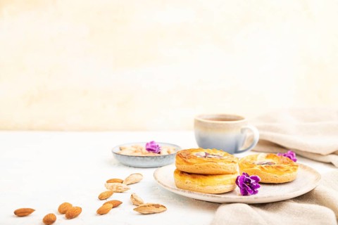 Small cheesecakes with jam and almonds with cup of coffee on a white concrete background and linen