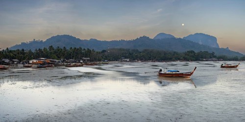 Before sunrise, longtail boats lie at low tide in the harbour at Sivalai Beach, Koh Mook Island,
