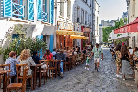 People enjoying a café outside on a cobbled village street, Paris
