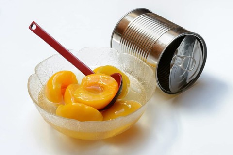 Peach, pickled peach halves in glass bowl with ladle and preserving tin