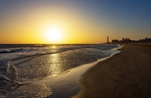 Sunset at the beach of Maspalomas with lighthouse Faro de Maspalomas, Gran Canaria, Canary Islands,