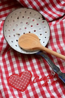 Dish drainer and cooking spoon on kitchen towel with lettering 'Cucina di mamma'