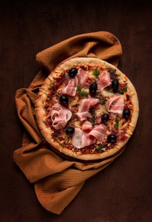 Pizza with prosciutto and mushrooms, bacon, olives, homemade, top view, no people