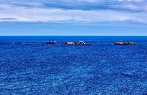 Calm of the deep blue sea with several small islands on the horizon, Malin Head