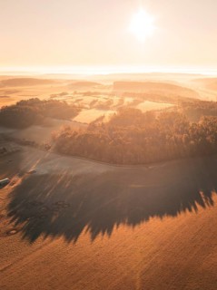Aerial view of a sunny morning over an extensive landscape with fields and trees, Gechingen
