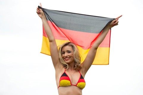 Young woman, blonde, football fan, bikini, black-red-gold, laughing, holding German flag,