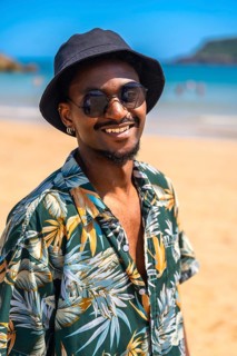 Young man wearing sunglasses and a bucket hat, smiling and enjoying a carefree summer vacation on a