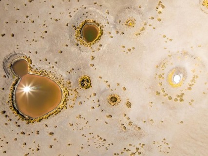 Top view, an aerial drone captures the sun reflecting in the pools of Salar de Antofalla in